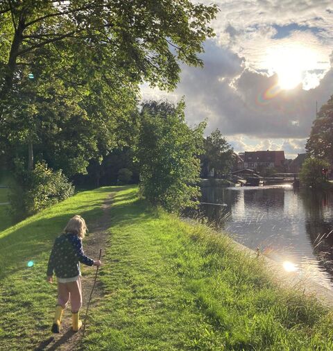 Ein Kind geht entlang eines Kanalas bei Sonnenuntergang. Fotocredit: Florian Leppla Ein Kind geht entlang eines Kanalas bei Sonnenuntergang